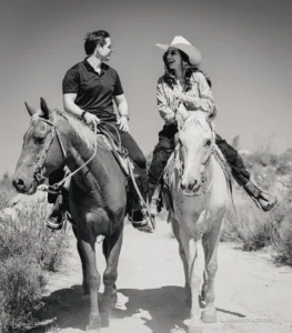 Jinetes a caballo en un sendero rocoso con vista a los viñedos del Valle de Guadalupe, Baja California